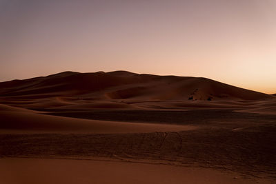 Amazing view of sand dunes in desert against clear sky during sunset