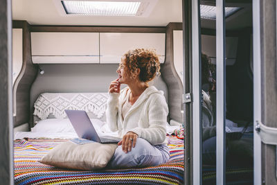 Side view of young woman sitting on bed