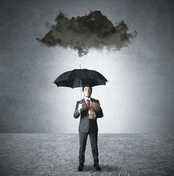 Full length portrait of man standing on wet umbrella