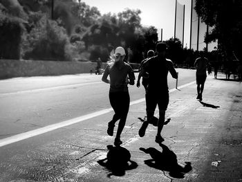 Rear view of people running on road