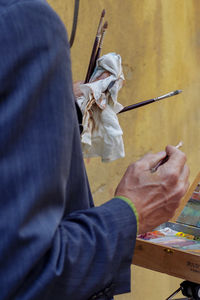 Midsection of man holding paintbrushes