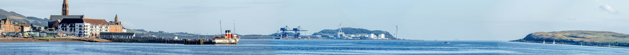 Sailboats in city by buildings against sky