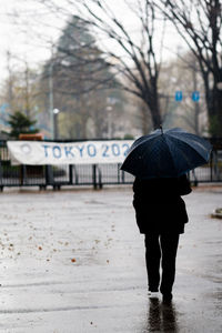 Rear view of man walking with umbrella