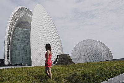 Rear view of woman standing against cloudy sky