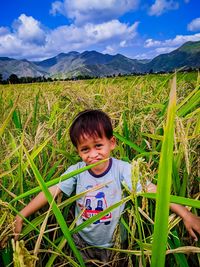 Portrait of boy standing on field against mountain