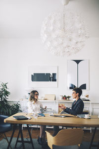 Businesswomen discussing while sitting at table in office