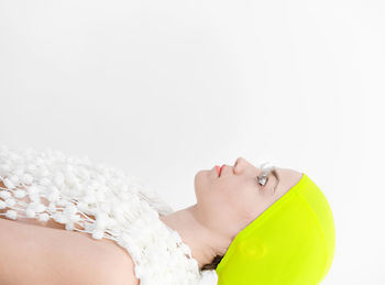 Side view of thoughtful woman lying against white background