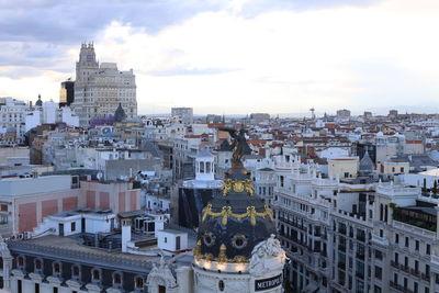 Buildings in city against cloudy sky