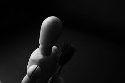 Close-up of hand holding leaf against black background