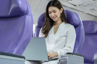 Smiling businesswoman using laptop while traveling in flight