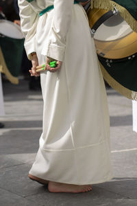 Low section of woman holding drumsticks while standing outdoors