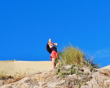 Woman standing on a hill against clear sky