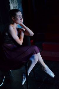 Ballet dancer sitting on chair in studio