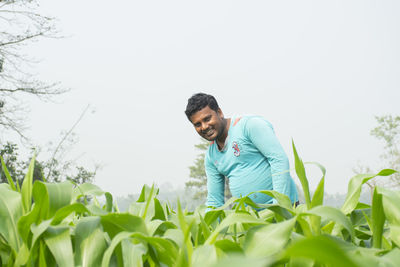 Young man smiling on field against sky