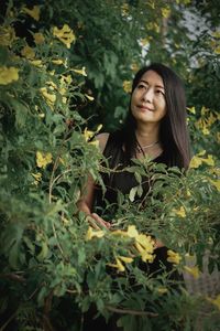 Portrait of young woman standing amidst plants