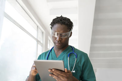 Young doctor wearing smart glasses and using tablet pc in hospital