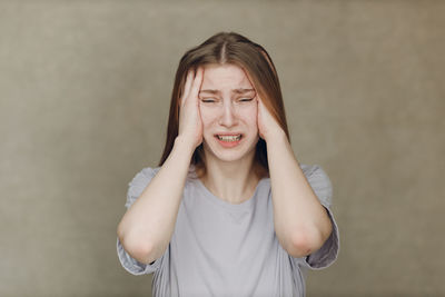 Portrait of young woman standing against wall