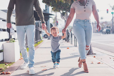 Family of three walking in downtown, baby boy walking with parents