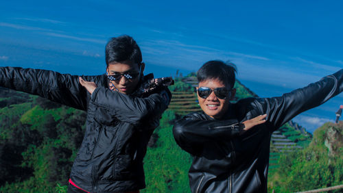 Portrait of friends wearing sunglasses gesturing against sky