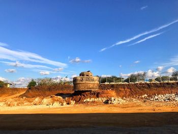 Built structure on landscape against blue sky