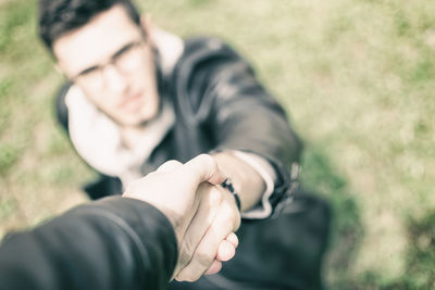 Close-up of couple with holding hands on field