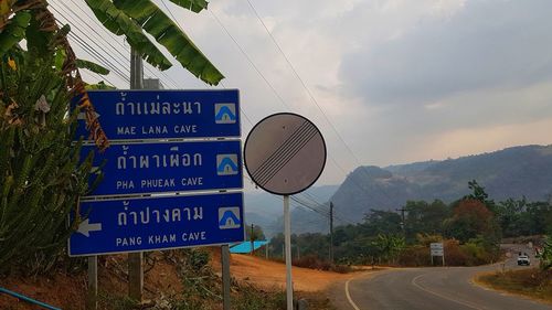 Information sign by road against sky