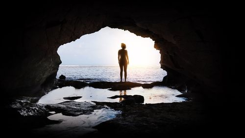 Silhouette man standing on rock in sea