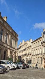 Cars on street amidst buildings in city against sky