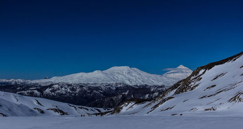 Scenic view of snow covered mountains against blue sky