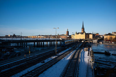 High angle view of railroad tracks by river against blue sky