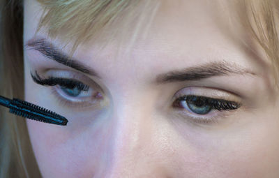 Close-up of young woman applying mascara