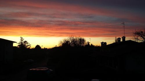 Silhouette trees and buildings against sky during sunset