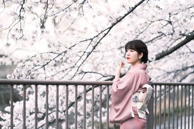 Side view of woman looking away while standing on railing