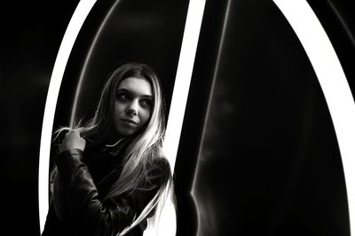 Close-up of woman standing against illuminated wall