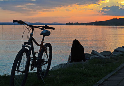 Bicycle sitting on beach against sky during sunset