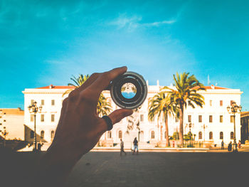 Close-up of hand holding lens against building