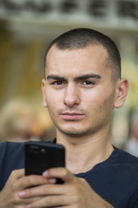 Portrait of serious teenage boy using mobile phone