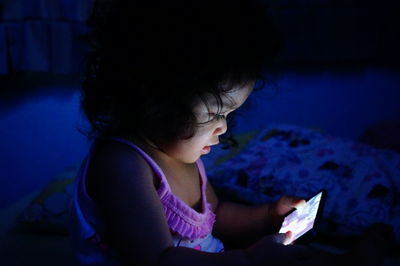 Side view of girl using smart phone while sitting at home