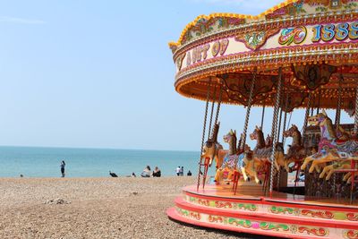 Carousel at sea against clear sky