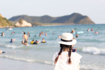 Rear view of people on beach against sky