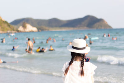 Rear view of woman at beach against sky