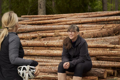 Cyclists resting on logs in forest