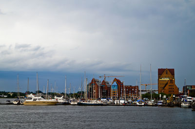 Boats moored at harbor against sky