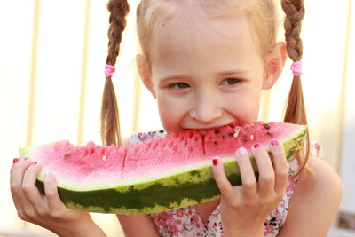 Little girl with pigtails eating delicious watermelon on the street