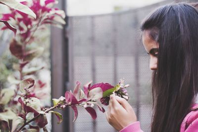 Close-up of young woman holding flowering plant at park