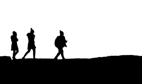 Silhouette people walking on land against clear sky