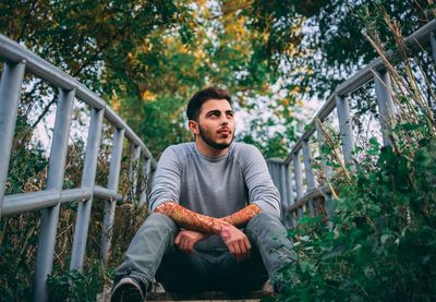 Portrait of young man sitting against plants