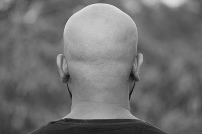 Close-up of completely bald man against tree
