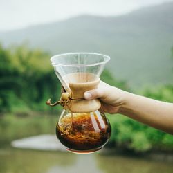 Close-up of hand holding drink against glass