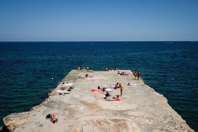 People on beach against clear blue sky